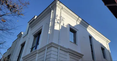 Bela kuća na sprat sa okvirima oko prozora, vencem ispod krova i lajsnom između spratova, snimljena odozdo