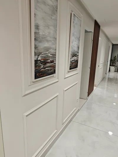 Beli zid sa ram lajsnama i velikim apstraktnim slikama u dugom hodniku sa sjajnim podom