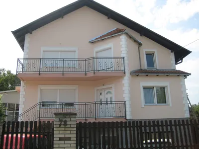 Kuća na sprat u boji breskve sa belim fasadnim lajsnama oko prozora, kockama na uglovima i balkonima