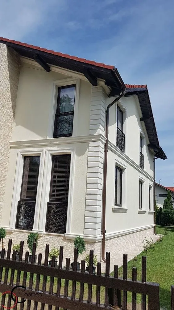 Fasada oko prozora: beli okviri i kocke na krem kući Kuća u krem boji sa belim okvirima oko prozora, kockama na uglu i soklom od stiropora