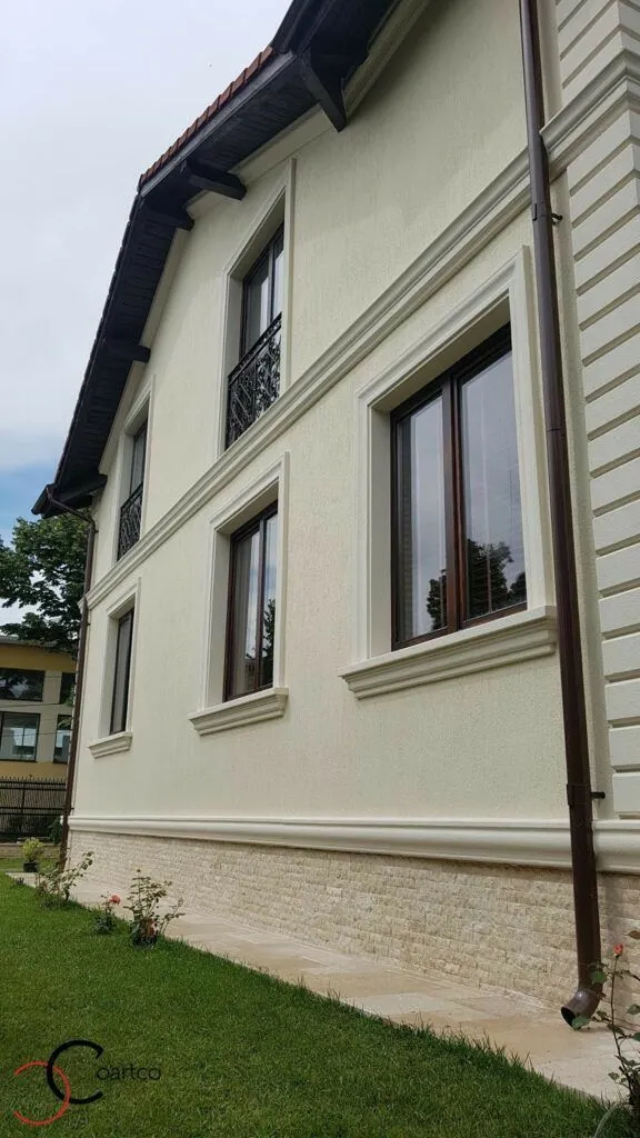 Fasade kuća na sprat: okviri prozora i venac između spratova Kuća na sprat sa svetlom fasadom, okvirima oko prozora, vencem između spratova i kamenim podnožjem