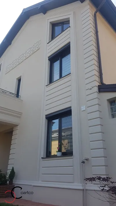 Kuća na sprat sa fasadnim kockama na uglu, okvirima oko prozora i ukrasnim frizom ispod krova