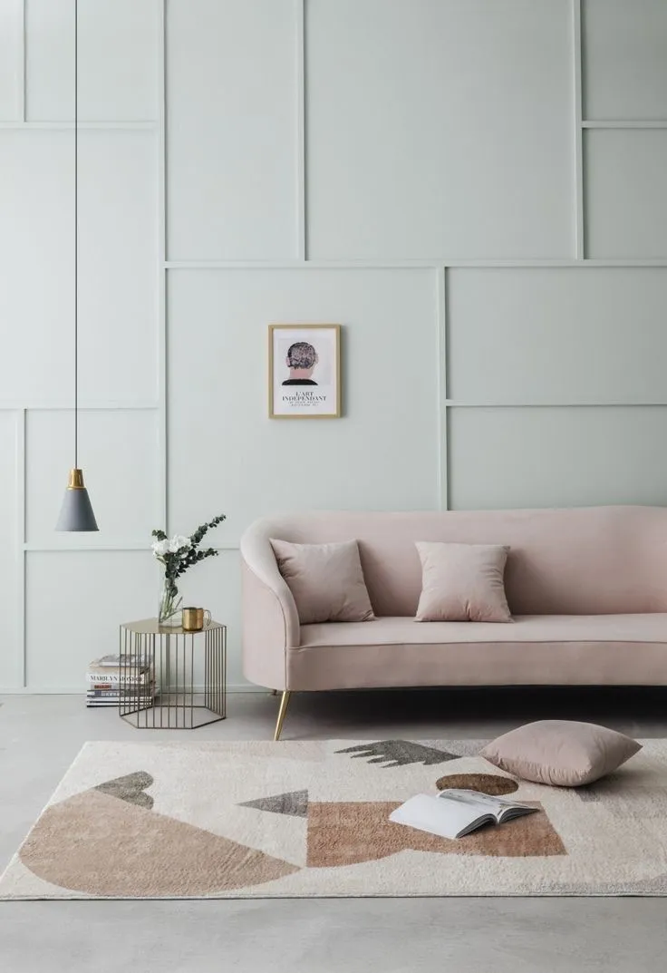 Geometrijske lajsne na svetlo zelenom zidu i roze sofa Svetlo zeleni zid sa geometrijskim lajsnama u različitim pravougaonicima, roze sofom i visećom lampom