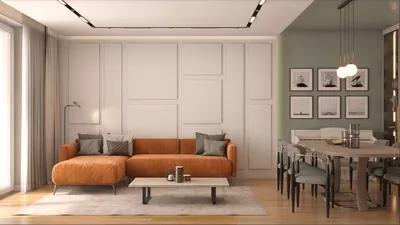 Dnevna soba sa geometrijskim ram lajsnama na belom zidu iza narandžaste ugaone garniture i trpezarijom pored
