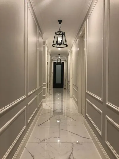 Dugačak hodnik sa ram lajsnama od stiropora na oba zida, mermerni pod i viseća lampa: ideja za uređenje hodnika
