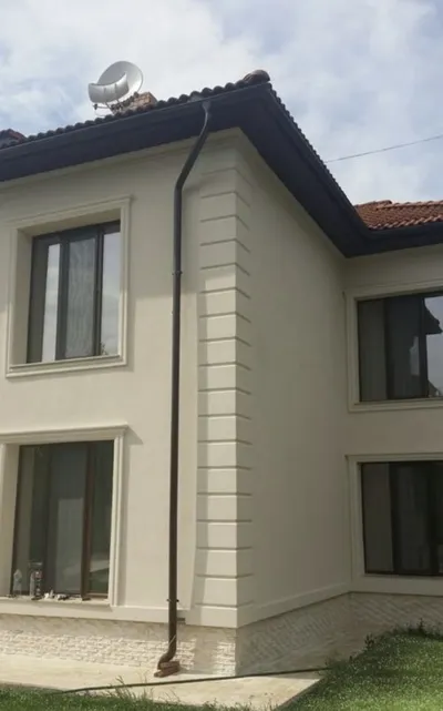 Kuća u krem boji sa pilastrima na uglovima, okvirima oko prozora i kamenim soklom