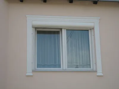 Beli okvir od stiropora oko prozora na fasadi boje breskve, sa podprozornom lajsnom: jednostavan ukras fasade