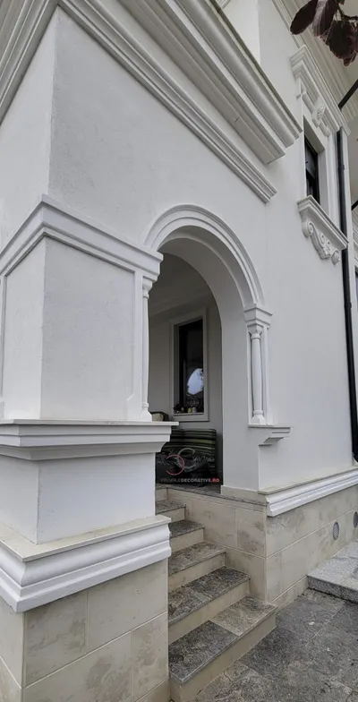 Bela fasada sa lučnim ulazom uokvirenim lajsnama, pilastrima sa strane i vencem iznad, stepenice od kamena