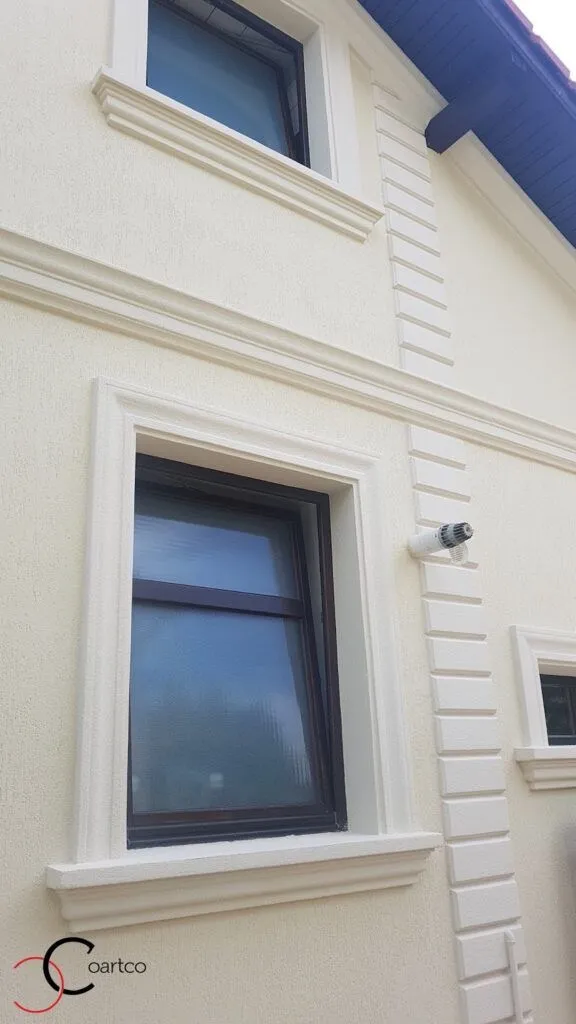 Okviri prozora i podprozornici na krem fasadi sa kockama Krem fasada sa belim okvirima oko prozora, podprozornicima i kockama na uglu kuće