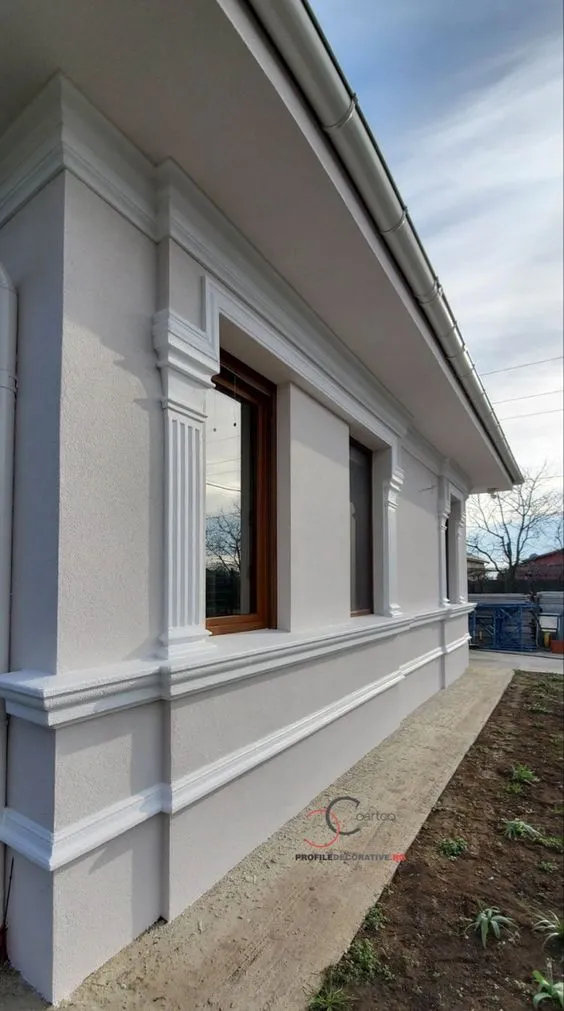 Stubovi na fasadi: pilastri, okviri prozora i sokla bele kuće Bočna strana bele kuće sa fasadnim pilastrima, okvirima oko prozora i soklom od stiropora