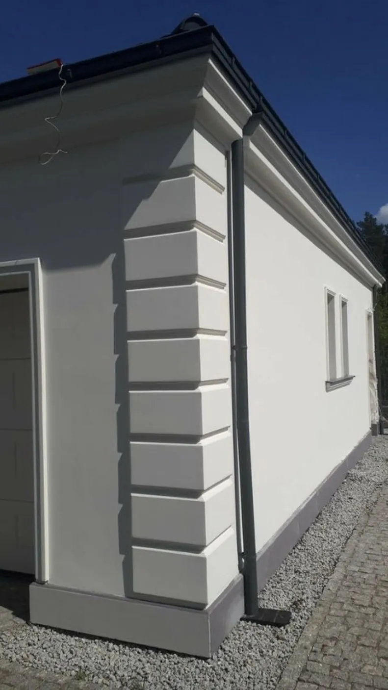 Velike horizontalne kocke na uglu bele prizemne kuće Ugao bele prizemne kuće sa velikim horizontalnim fasadnim kockama celom visinom zida